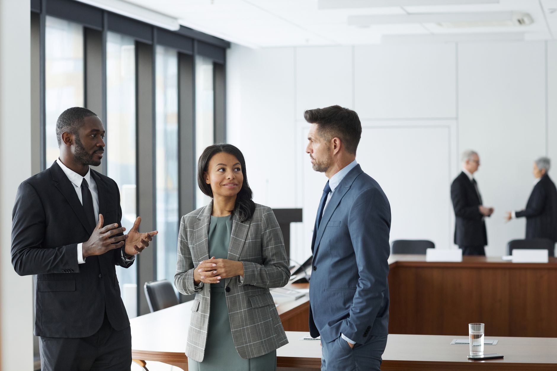 Three colleagues reviewing a sales playbook document at a small office desk